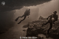 2 divers exploring an overhang by Petra Van Borm 